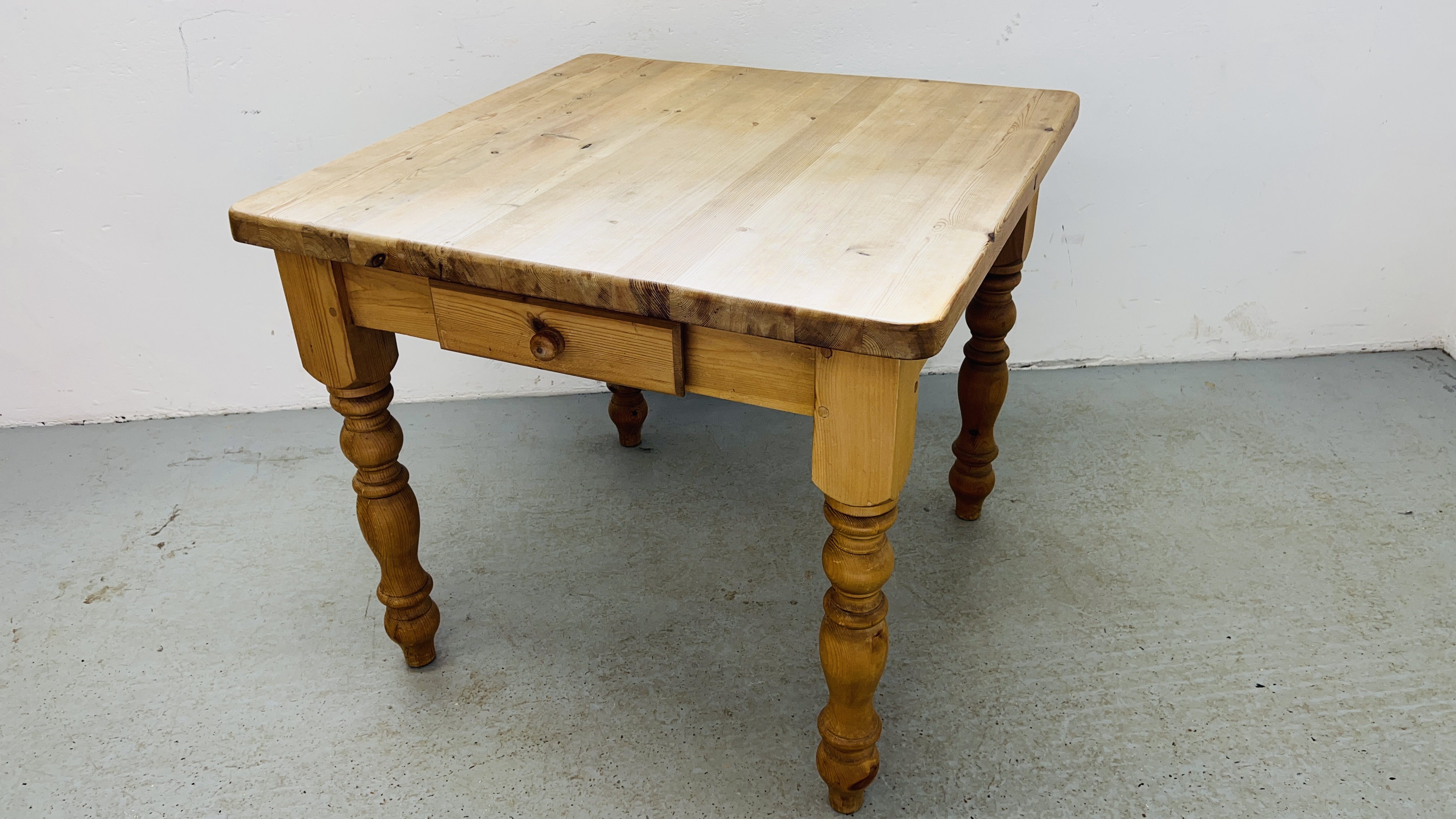 A MODERN HEAVY SOLID PINE KITCHEN TABLE ON TURNED LEGS WITH DRAWER W 90CM, D 91CM.