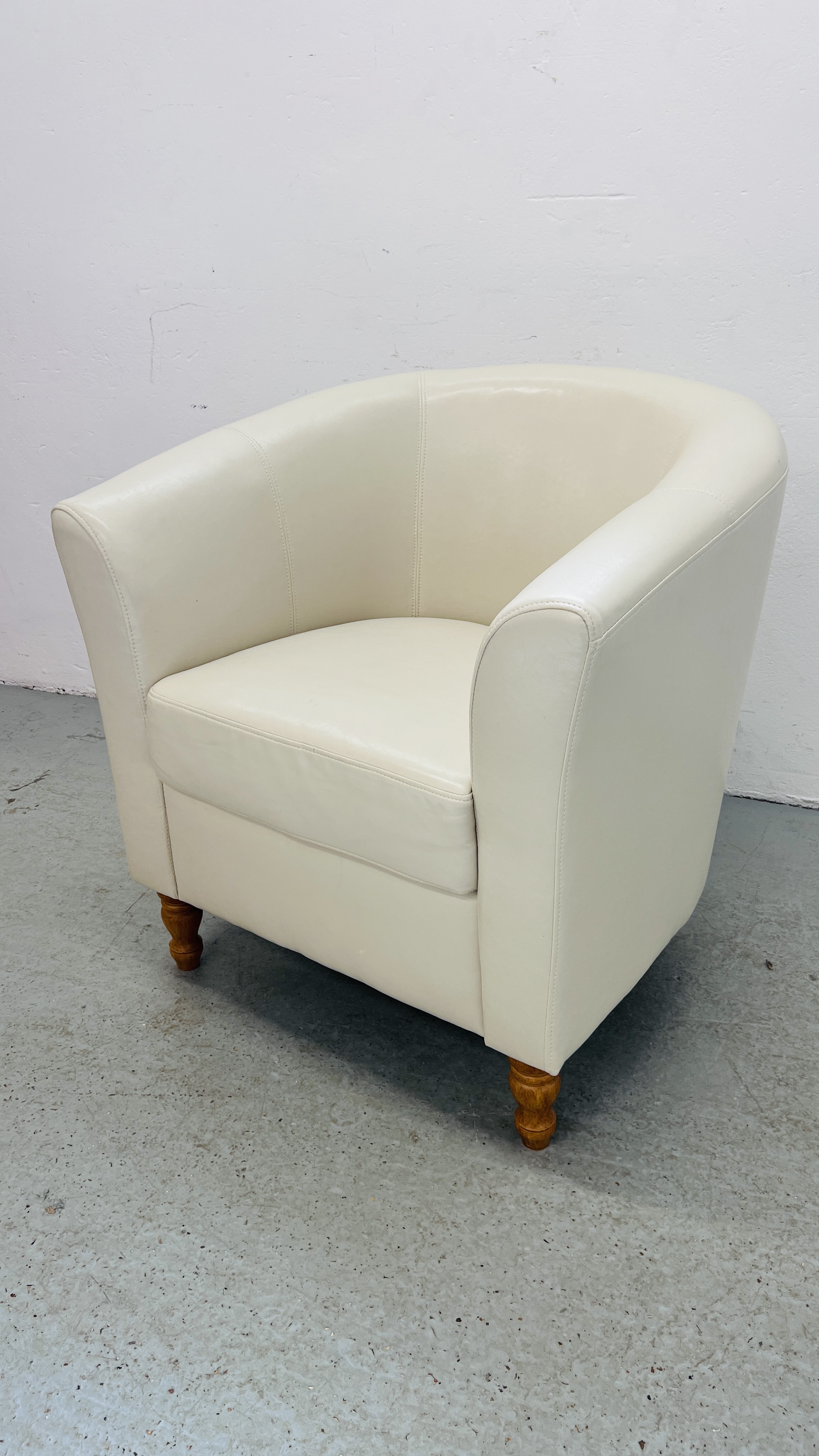 A MODERN CREAM FAUX LEATHER TUB CHAIR.