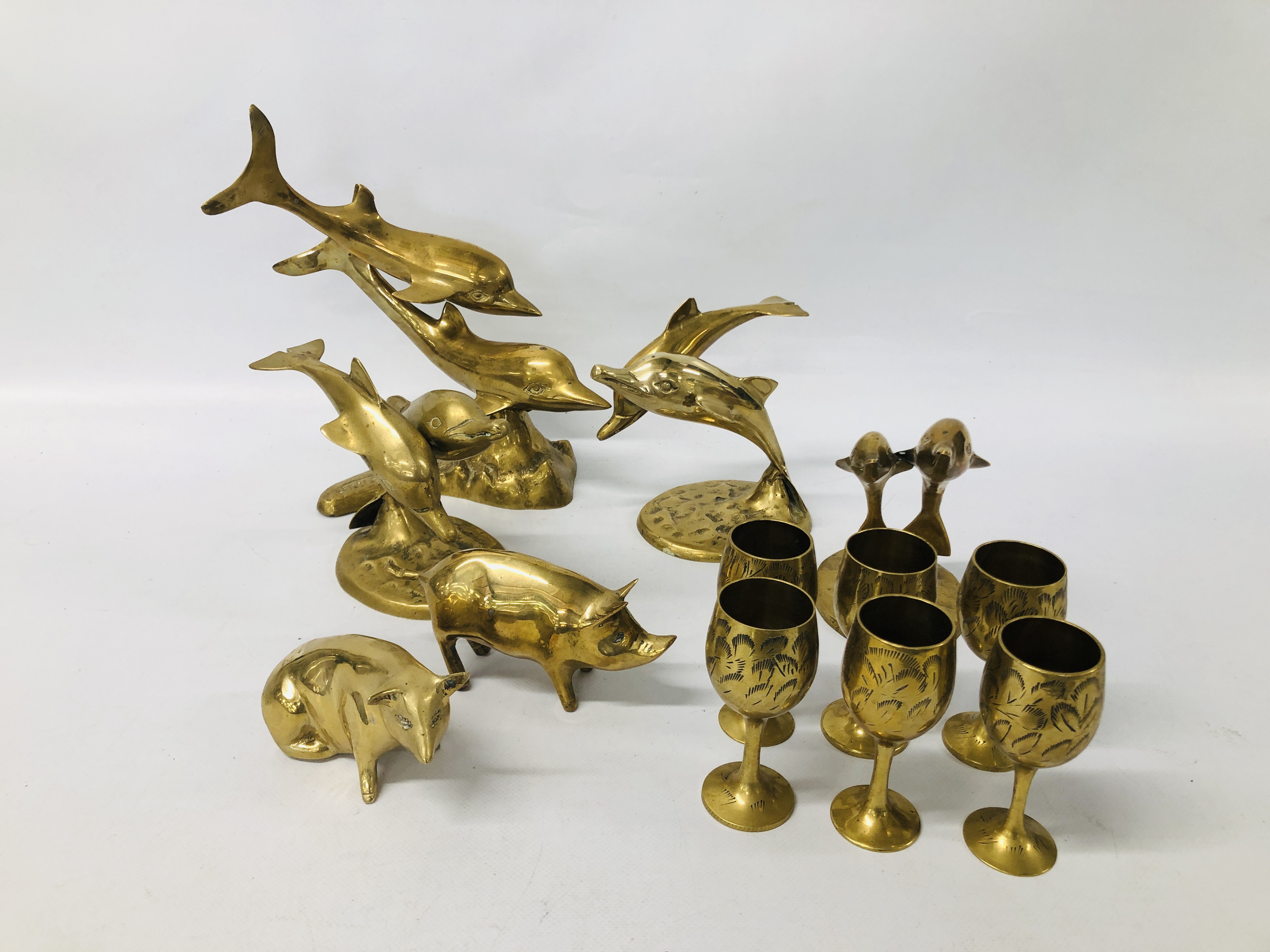 COLLECTION OF BRASS DOLPHINS, PIGS AND GOBLETS.