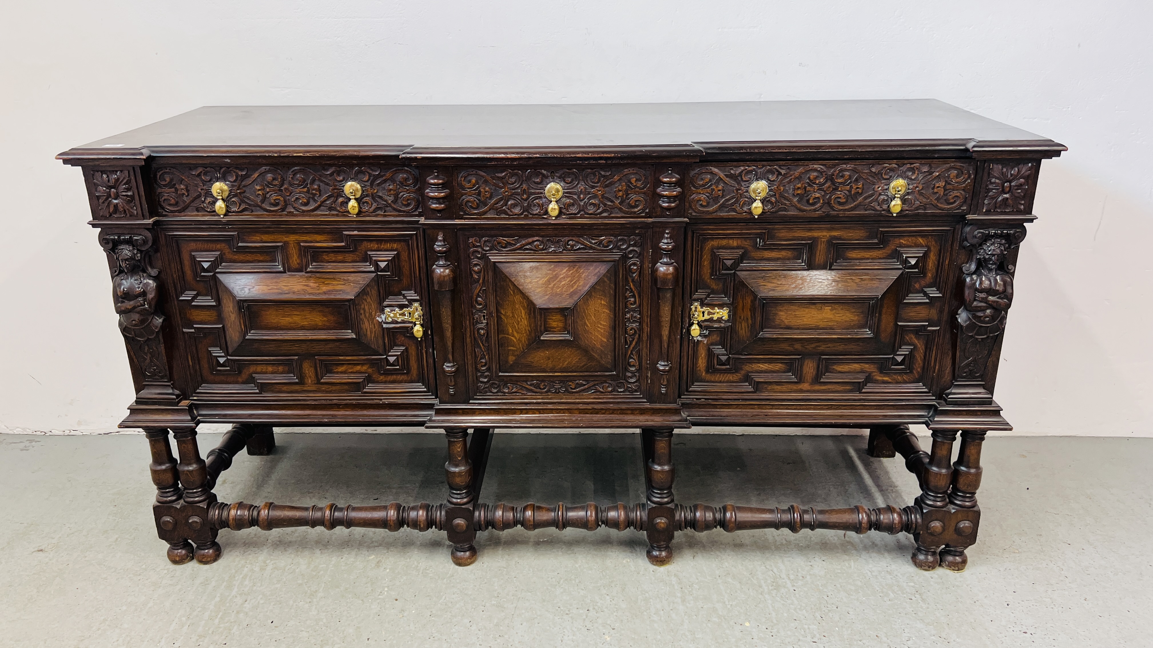 A C20TH CARVED OAK SIDEBOARD IN C17TH STYLE BY HAMPTONS OF LONDON W 198CM, D 66CM, H 101CM.