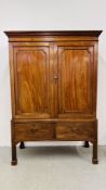 AN ANTIQUE VICTORIAN MAHOGANY TWO DOOR MAID'S CUPBOARD WITH SHELVED INTERIOR ON TWO DRAWER RAISED