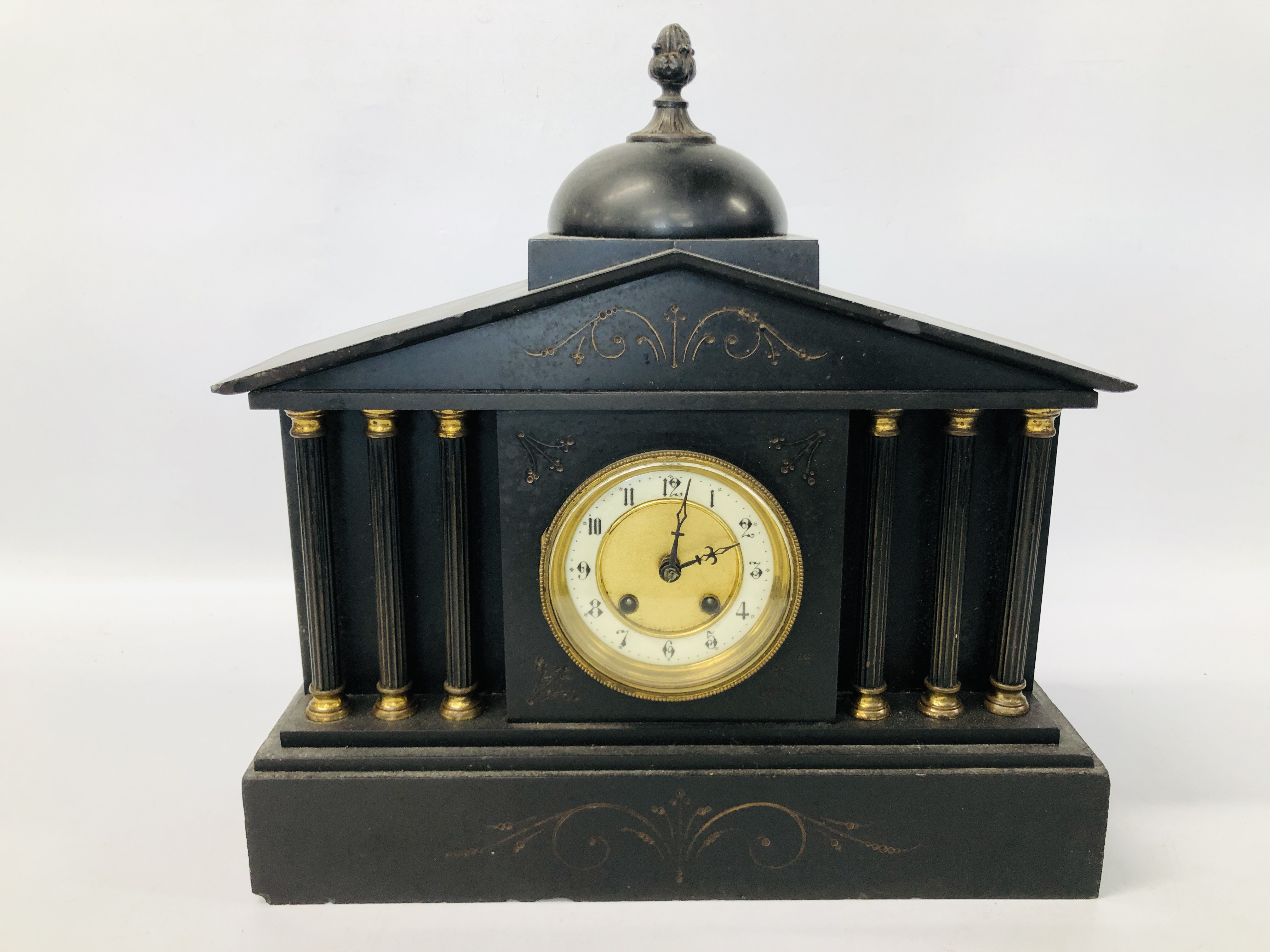 AN ANTIQUE SLATE MANTEL CLOCK WITH COLUMN SUPPORT AND ENAMELLED DIAL WITH PENDULUM (NOT CURRENTLY