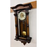 AN ANTIQUE STRIKING WALL HANGING CASED CLOCK WITH FLORAL DETAIL.