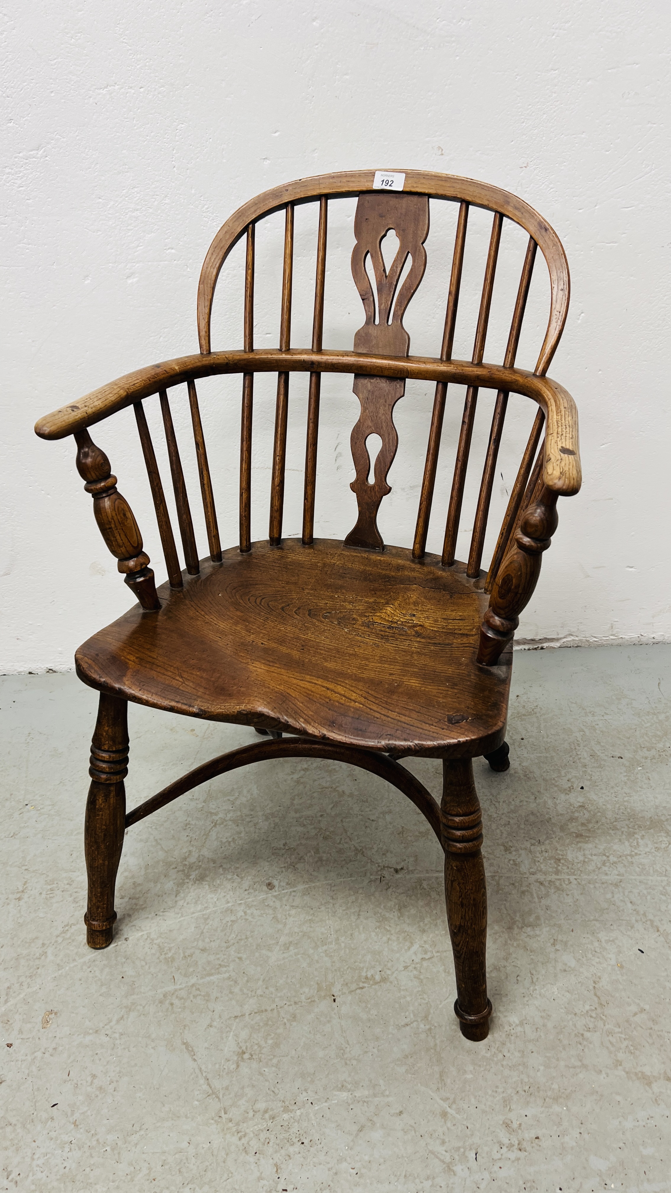 AN ANTIQUE ELM SEATED STICK BACK ELBOW CHAIR.
