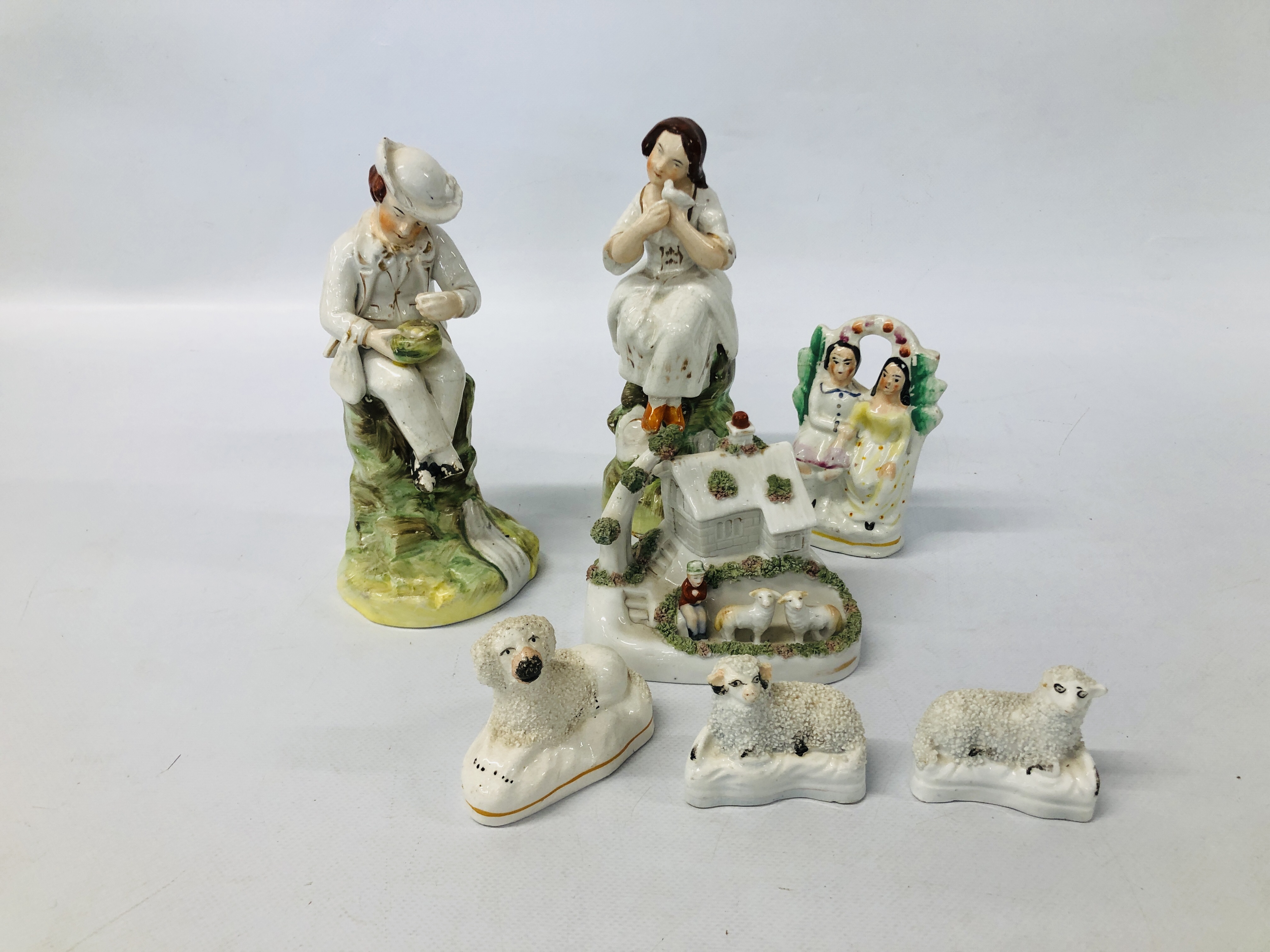 A PAIR OF STAFFORDSHIRE FIGURES A SEATED GIRL AND BOY (FOOT A/F HAIRLINE CRACK TO KNEE) EXTENSIVE