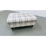 A MODERN OATMEAL UPHOLSTERED HINGE TOP FOOTSTOOL WITH CHECK PATTERN STANDING ON BRASS CASTERS 95 X