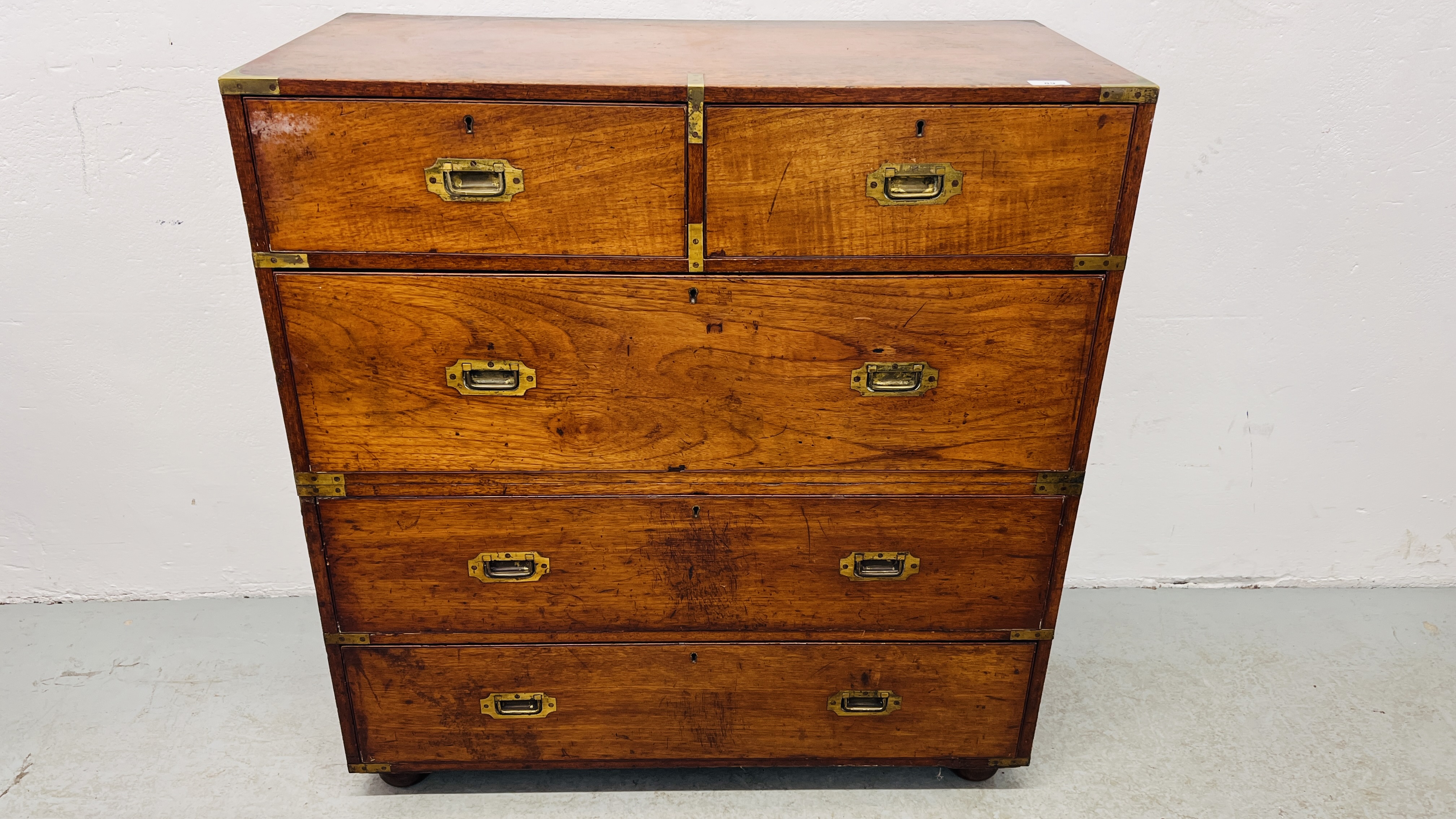 ANTIQUE MAHOGANY TWO OVER THREE CAMPAIGN CHEST ON BUN FEET WITH BRASS HANDLES AND BANDING BEARING