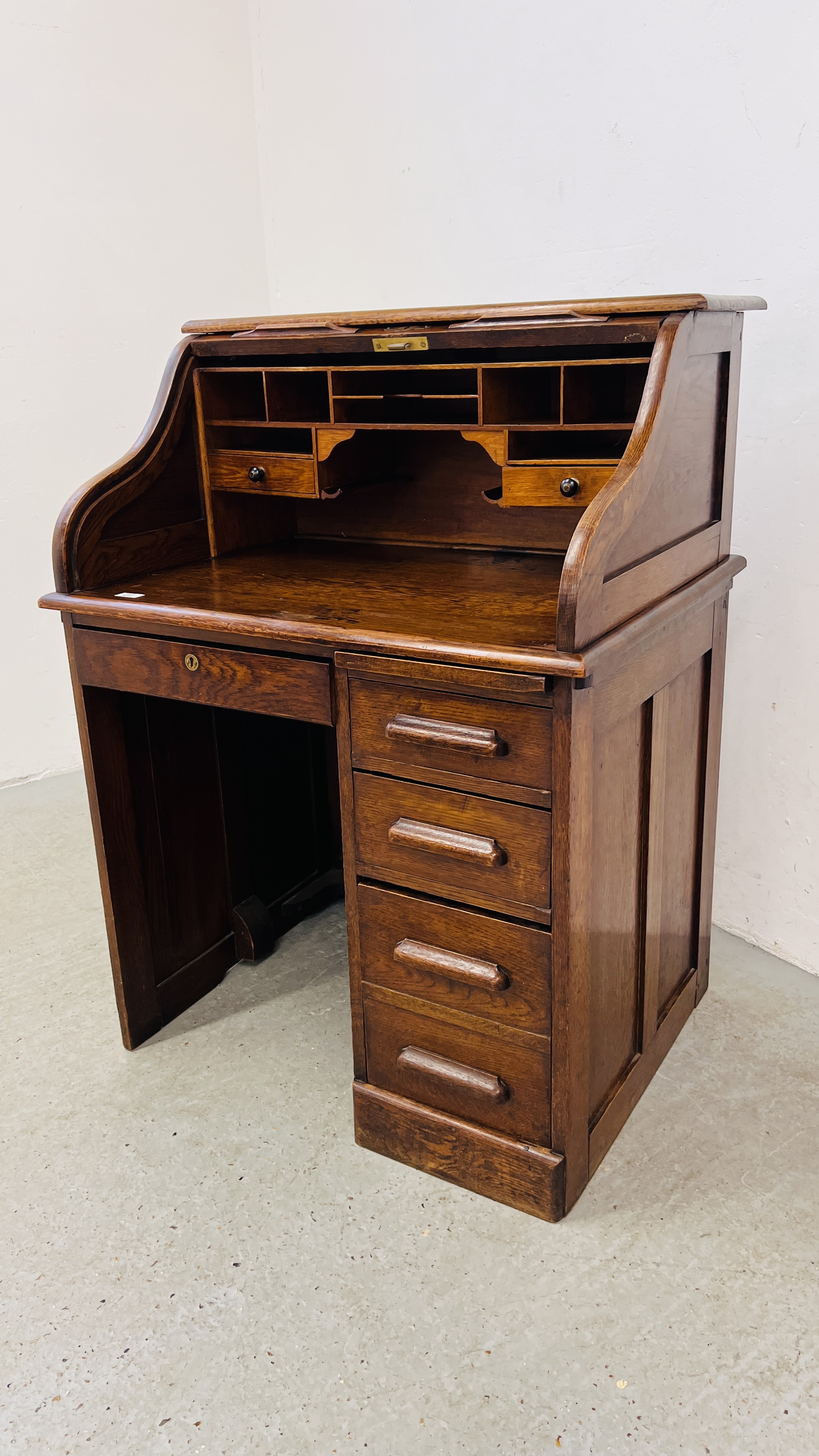 AN OAK FOUR DRAWER SINGLE PEDESTAL ROLL TOP DESK WITH FITTED INTERIOR W 84CM, D 65CM, H 113CM.