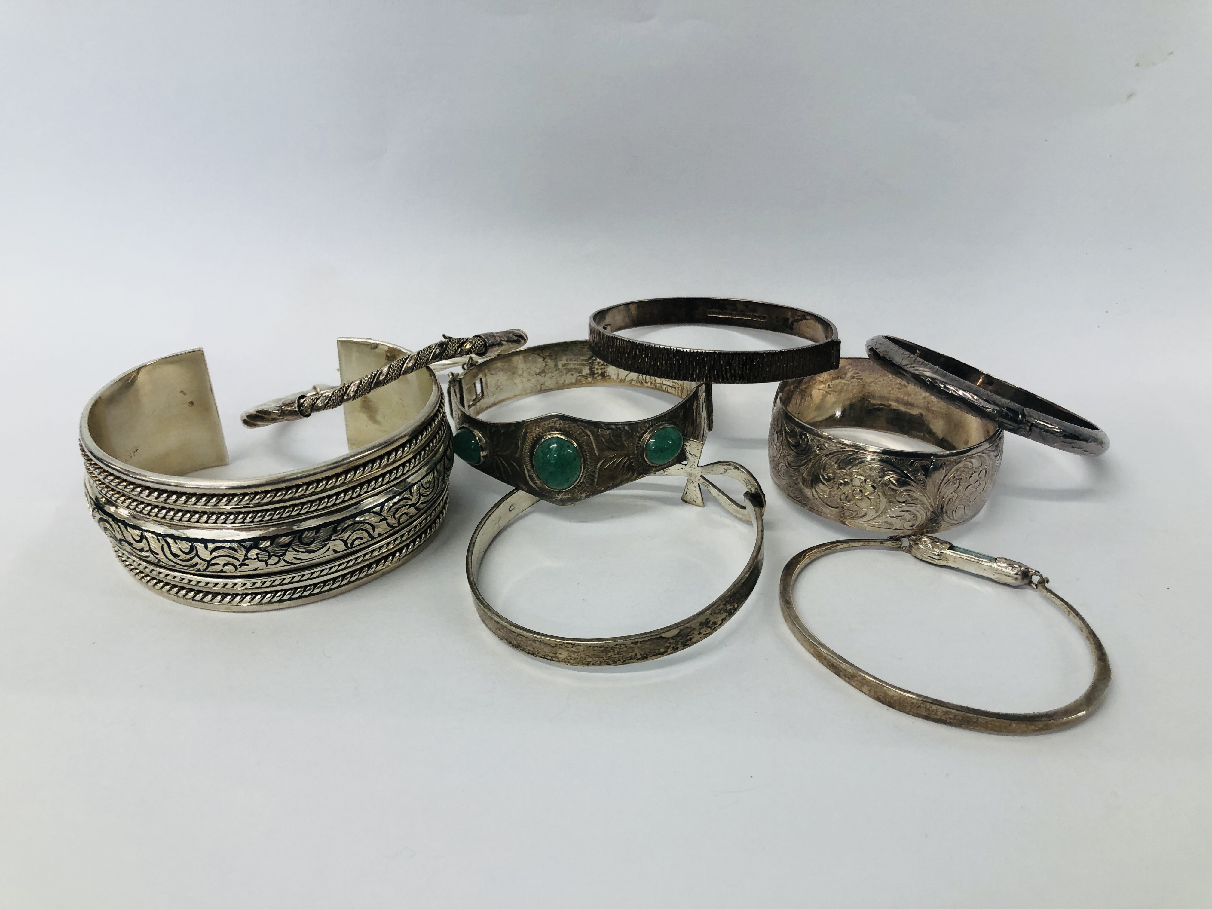 COLLECTION OF EIGHT ASSORTED SILVER BRACELETS AND BANGLES TO INCLUDE ONE SET WITH THREE JADE STONES.