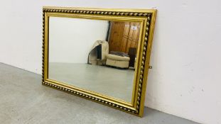 A LARGE GILT FRAMED DECORATIVE BEVELLED EDGE WALL MIRROR 76CM. X 106CM.