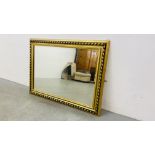 A LARGE GILT FRAMED DECORATIVE BEVELLED EDGE WALL MIRROR 76CM. X 106CM.