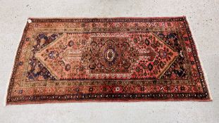A PERSIAN RUG THE CENTRAL HOOKED MEDALLION WITH PROJECTING ANCHOR DESIGN ON A RED FIELD - 195CM.