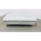 A LARGE PALE BLUE UPHOLSTERED HINGE TOP FOOT STOOL STANDING ON BRASS CASTERS - W 66CM. D 130 CM.