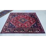 A PERSIAN RUG THE CENTRAL LOZENGE ON A RED STEPPED FIELD - 220CM. X 310 CM.