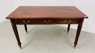 A REPRODUCTION HARDWOOD THREE DRAWER WRITING TABLE STANDING ON REEDED LEG - W 126CM. D 65CM. H 75CM.