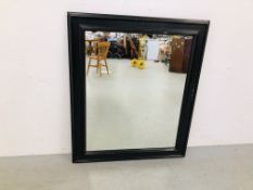 A LARGE BLACK FRAMED WALL MIRROR 112CM X 95CM.