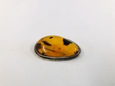 A SILVER MOUNTED AMBER BROOCH