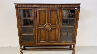 A 1930's OAK THREE DOOR CABINET STANDING ON LEG,