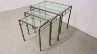SET OF THREE DESIGNER STAINLESS STEEL GLASS TOP GRADUATED OCCASIONAL TABLES.