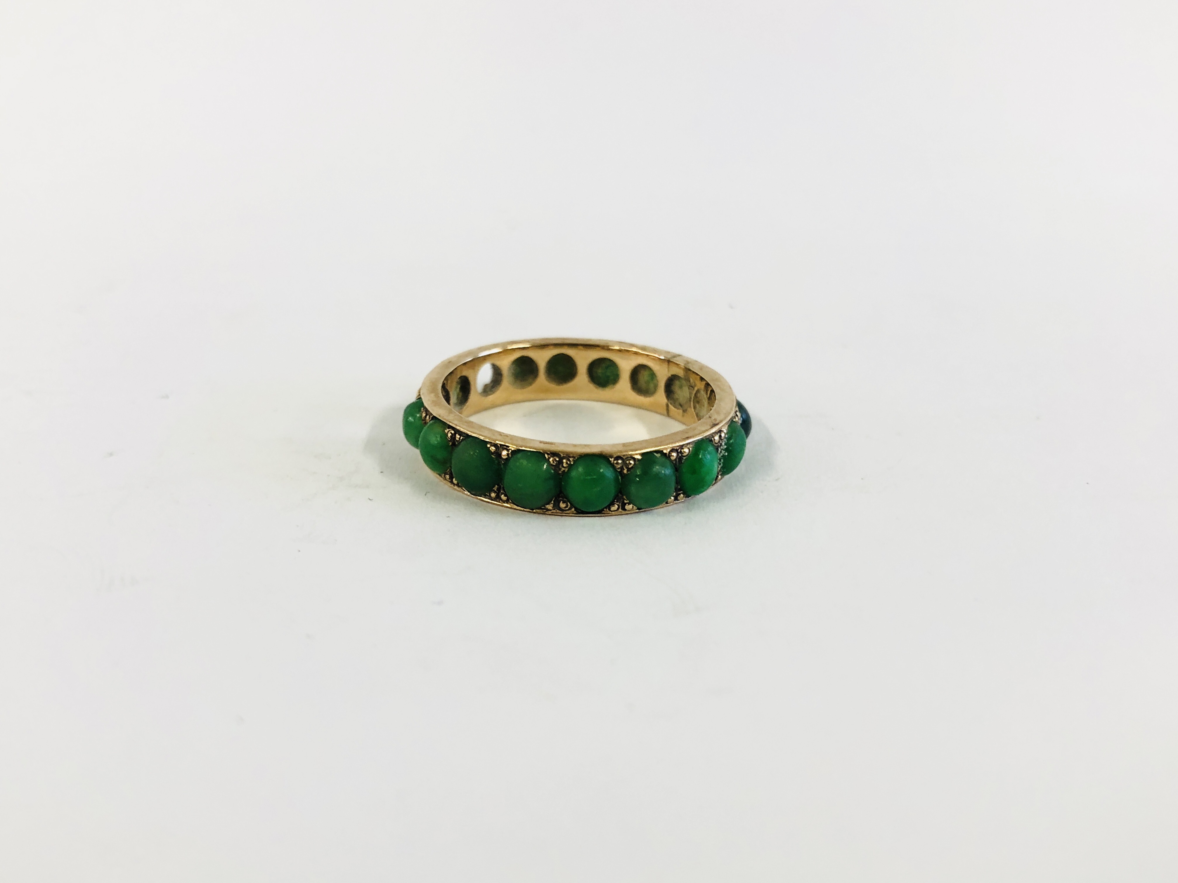 AN UNMARKED YELLOW METAL ETERNITY RING SET WITH JADEITE STONES (2 MISSING) SIZE N/O