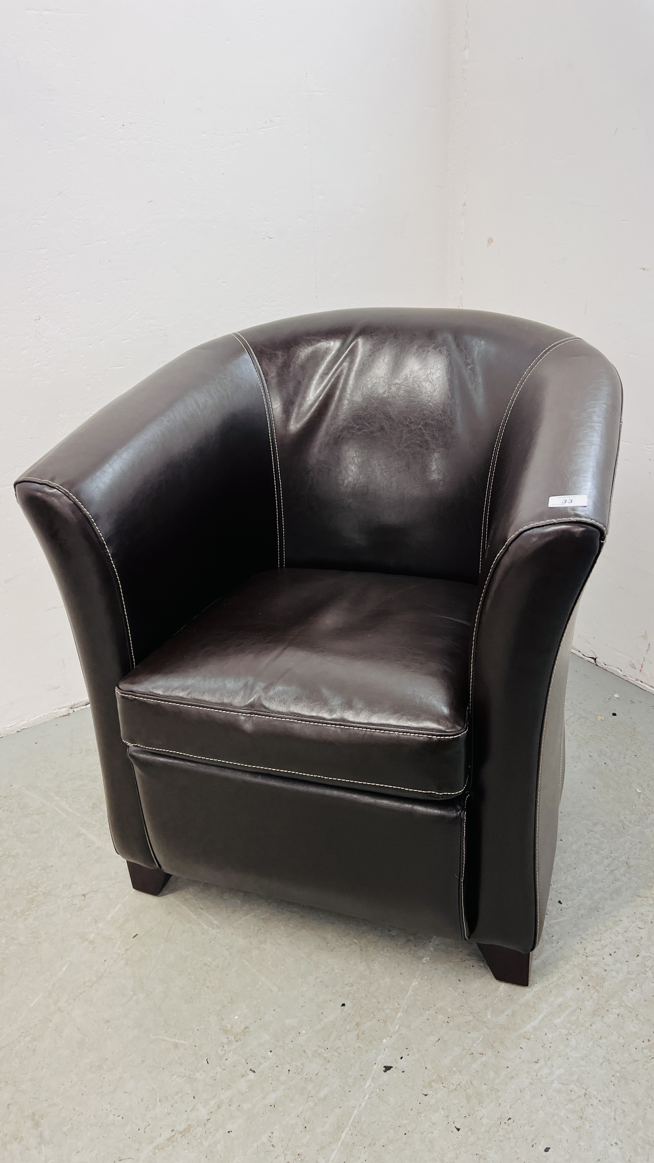 A DARK TAN FAUX LEATHER TUB CHAIR