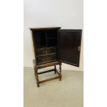 A SMALL OAK CABINET THE PANELLED DOOR CONCEALING INTERNAL DRAWERS STANDING ON BARLEY TWIST LEG,