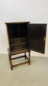 A SMALL OAK CABINET THE PANELLED DOOR CONCEALING INTERNAL DRAWERS STANDING ON BARLEY TWIST LEG,