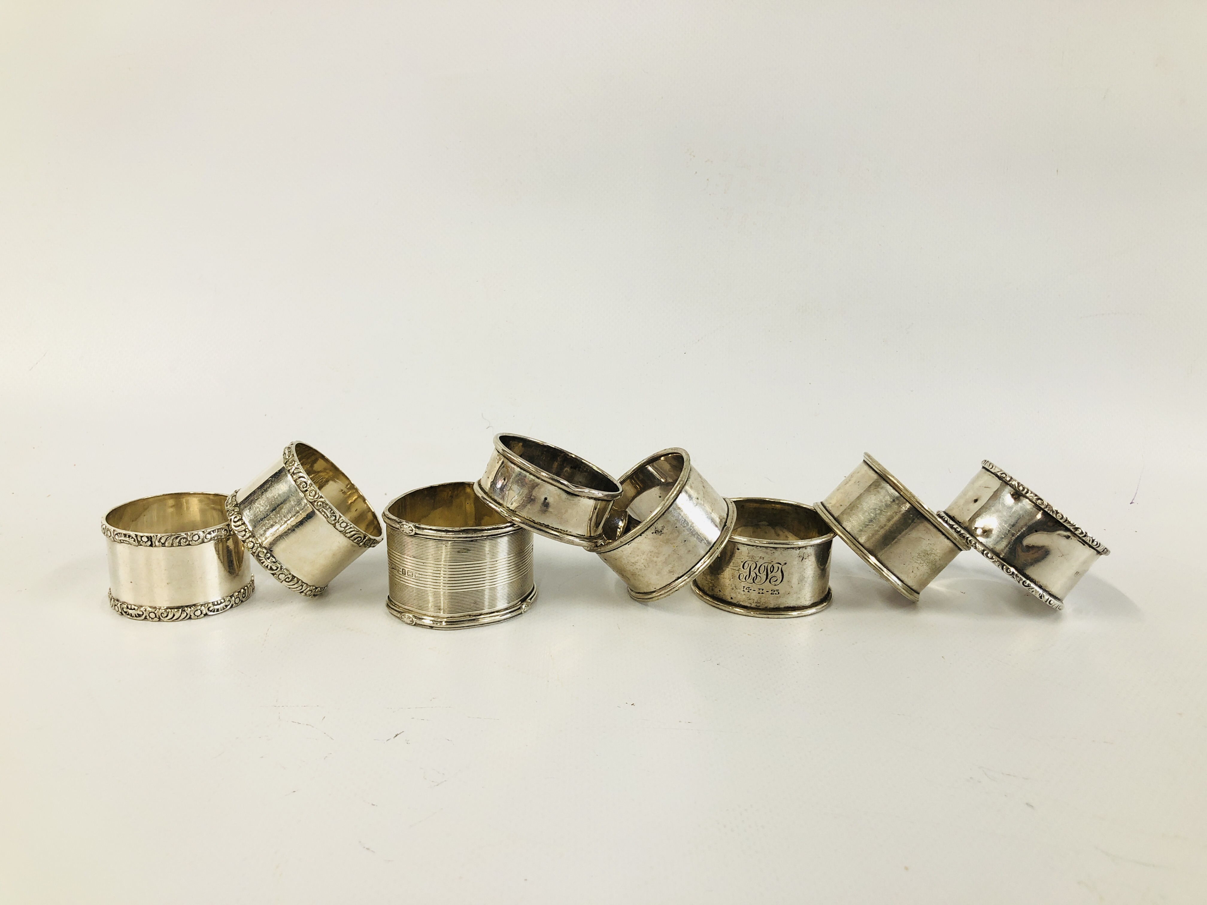 A GROUP OF FOUR SILVER NAPKIN RINGS ALONG WITH FOUR OTHERS UNMARKED