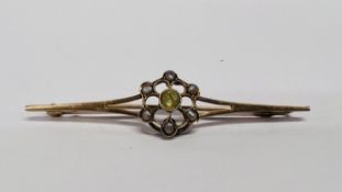 A 9CT GOLD BAR BROOCH SET WITH CENTRAL PERIDOT, SURROUNDED BY SEED PEARLS.