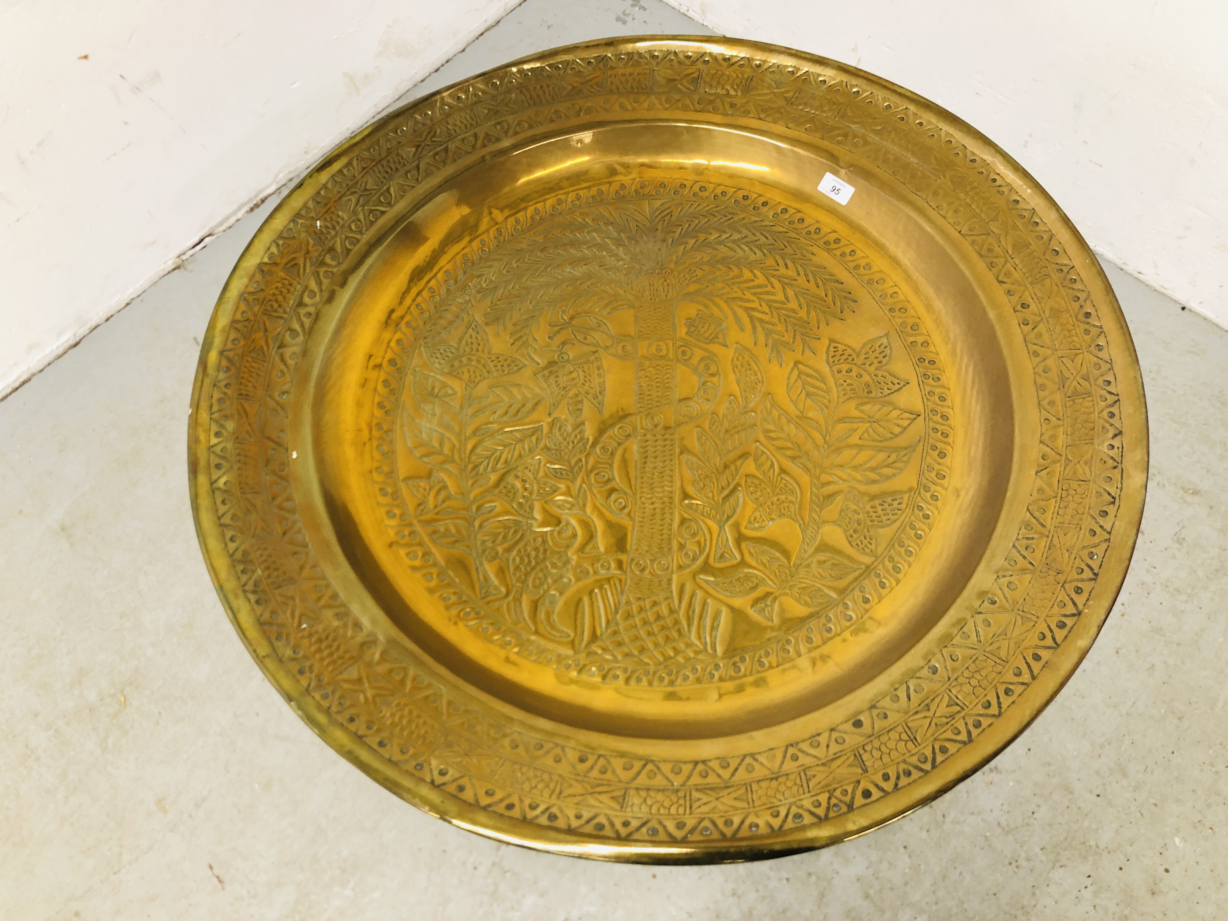 A LARGE BRASS EASTERN TRAY TABLE ON FOLDING CARVED WOODEN BASE (TRAY DIA. 91CM. - Image 3 of 5