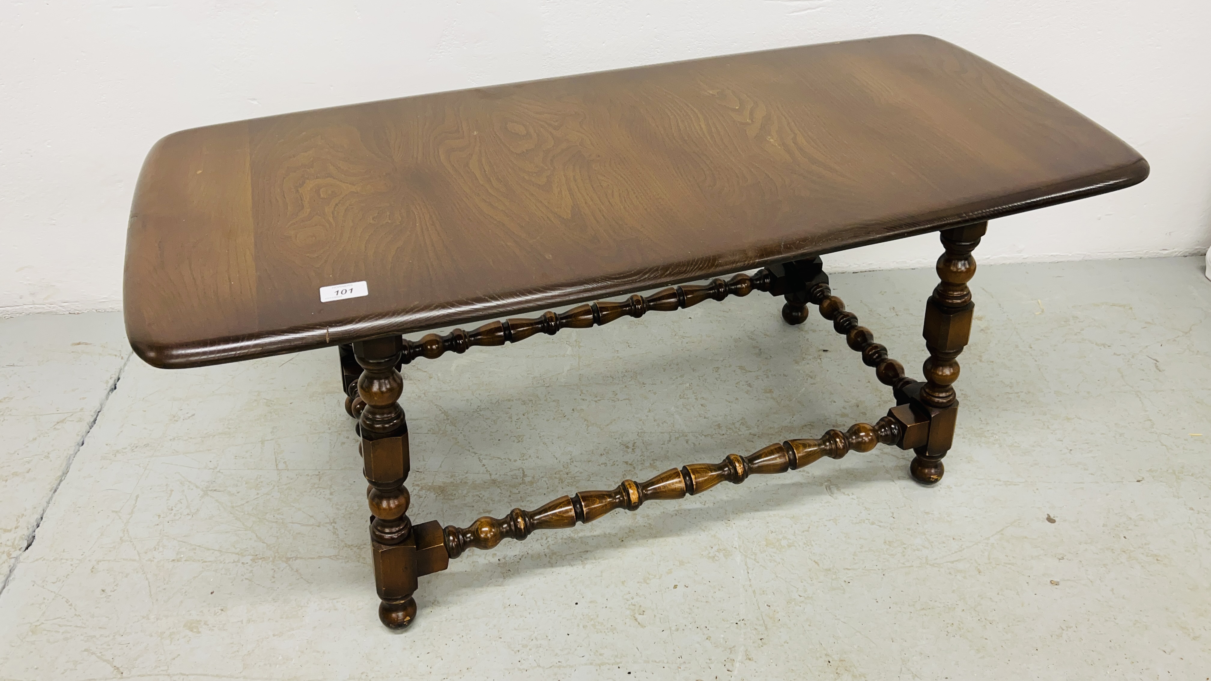 ERCOL RECTANGULAR COFFEE TABLE WITH TURNED SUPPORTS AND STRETCHERS WIDTH 45CM. LENGTH 104CM.