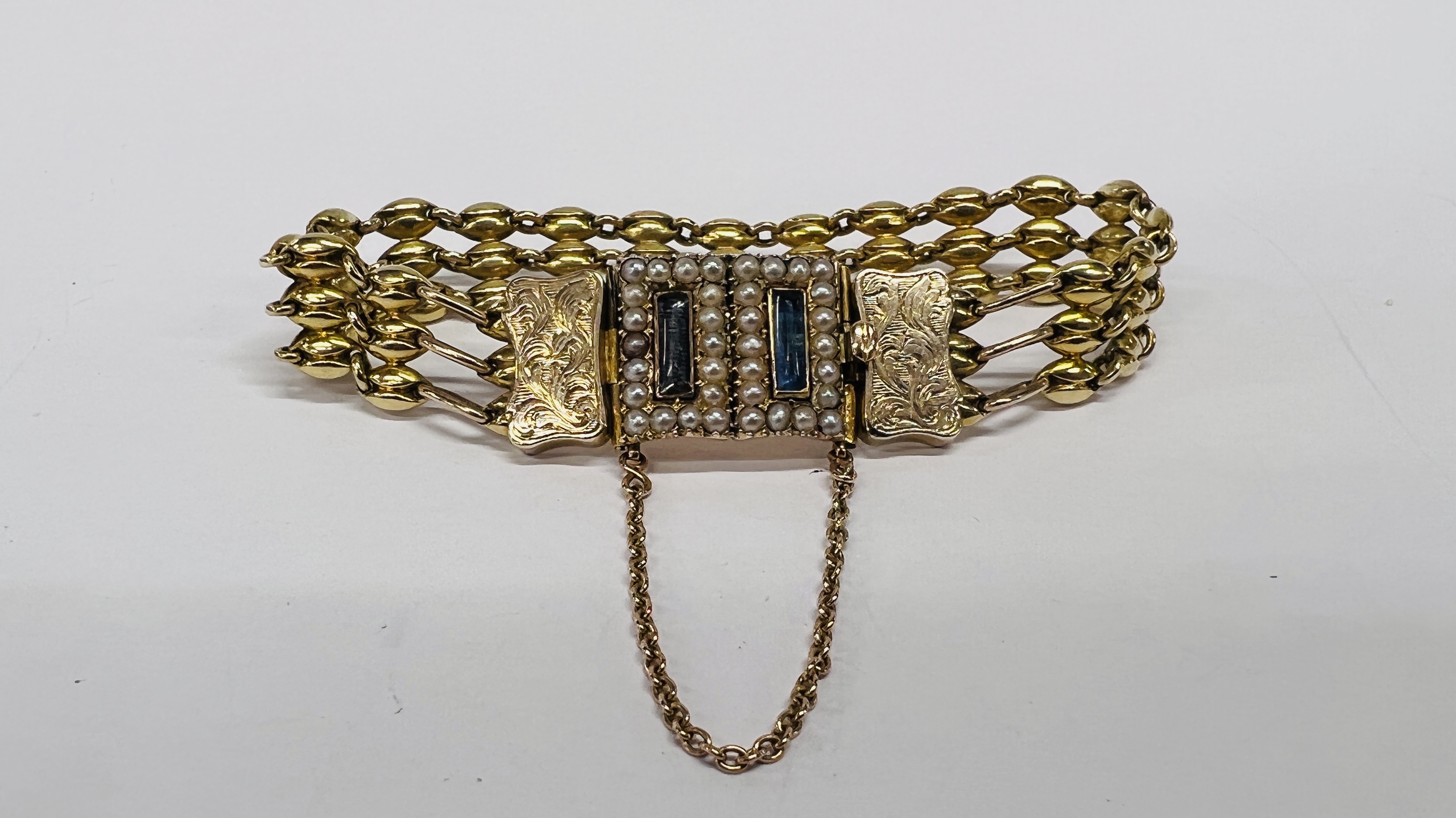 AN EDWARDIAN UNMARKED YELLOW METAL BRACELET, THE RECTANGULAR PANELS SURROUNDED BY SEED PEARLS,