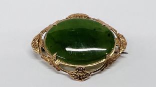 A YELLOW METAL BROOCH SET WITH A GREEN HARDSTONE, 4.25CM (RUBBED MARKS).