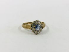AN ATTRACTIVE 9CT GOLD DRESS RING SET WITH CENTRAL PALE BLUE STONE, SURROUNDED BY SMALLER DIAMONDS.