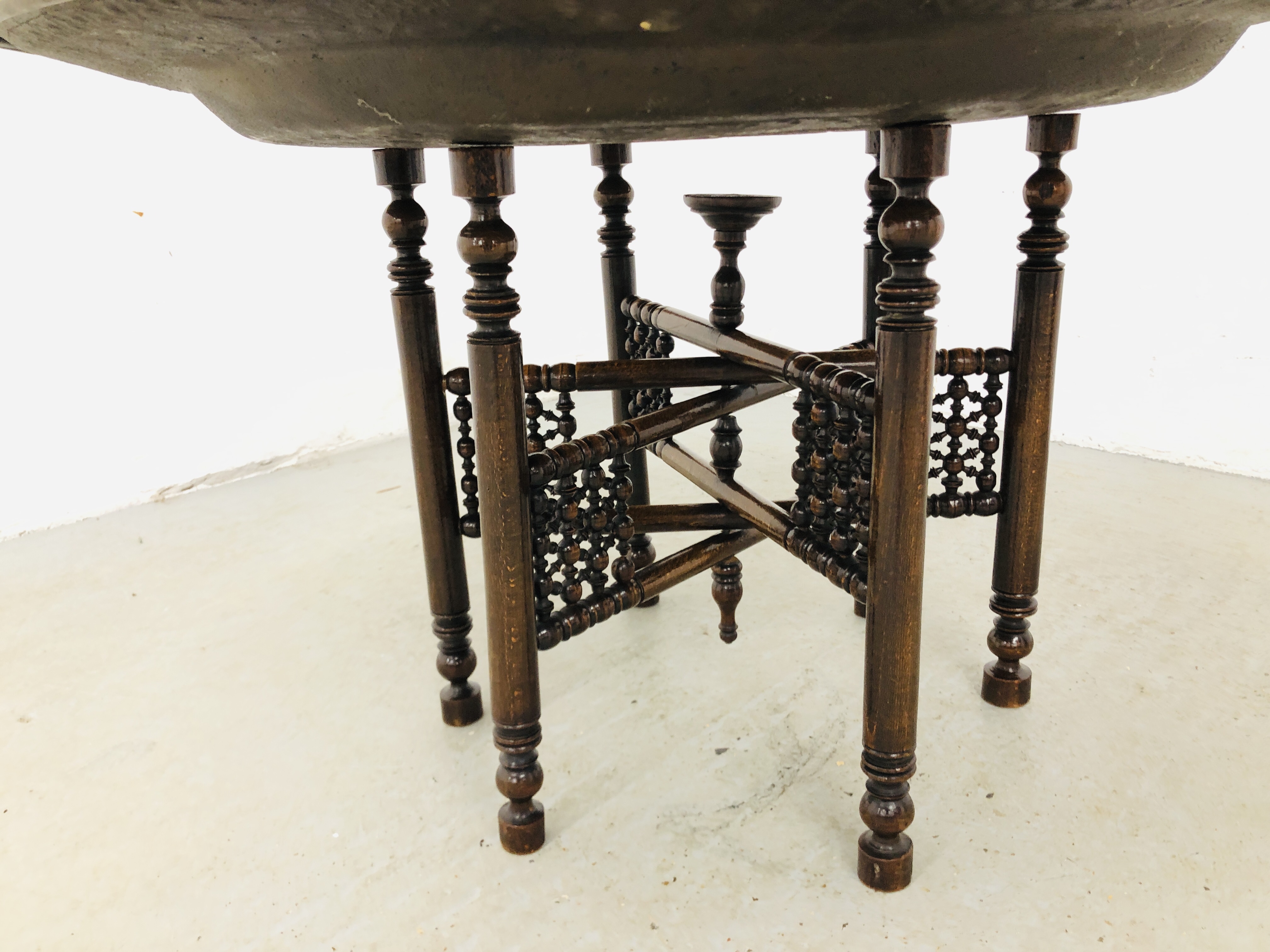 A LARGE BRASS EASTERN TRAY TABLE ON FOLDING CARVED WOODEN BASE (TRAY DIA. 91CM. - Image 2 of 5