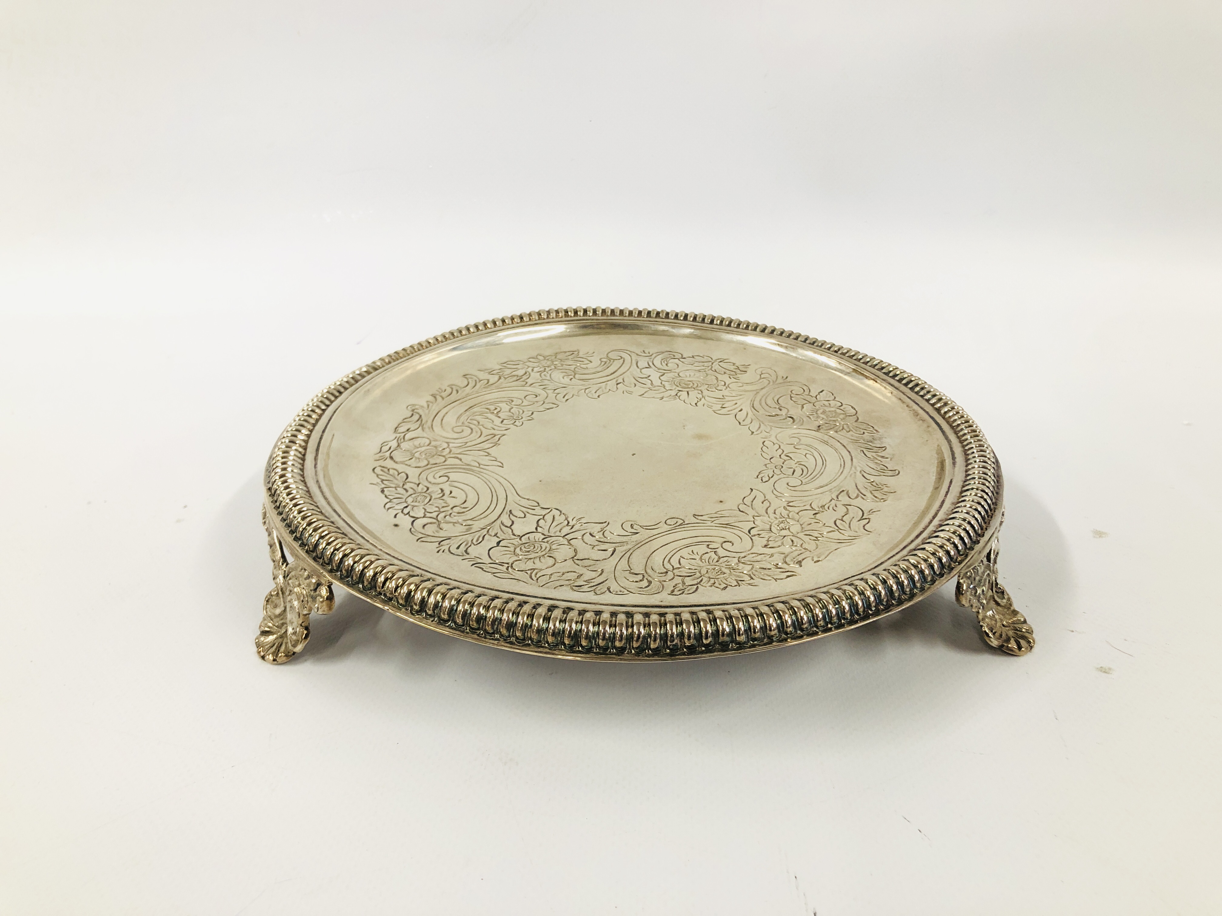 A SILVER CIRCULAR SALVER WITH NULLED RIM ON SCROLLED TRIPOD FEET BY JOESEPH WALKER OF DUBLIN C17