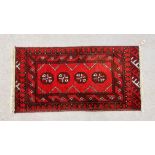 A SMALL RED PATTERNED EASTERN RUG 94CM. X 48CM.