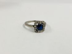 A ELEGANT VINTAGE RING SET WITH A CENTRAL BLUE STONE SURROUNDED BY DIAMONDS IN A SQUARE SETTING