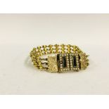 AN EDWARDIAN UNMARKED YELLOW METAL BRACELET, THE RECTANGULAR PANELS SURROUNDED BY SEED PEARLS,