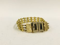 AN EDWARDIAN UNMARKED YELLOW METAL BRACELET, THE RECTANGULAR PANELS SURROUNDED BY SEED PEARLS,