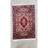 A SMALL PERSIAN BEDSIDE RUG 100CM. X 67CM.