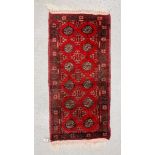 A SMALL AFGHAN RUG 103CM. X 51CM.