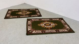 A PAIR OF MACHINE MADE RUGS ON A MAINLY GREEN BACKGROUND, W 90CM X L 153CM.