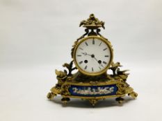 AN ORNATE BRASS MANTEL CLOCK WITH ENAMELLED CHERUB DETAILED PANEL AND NESTING BIRDS STANDING ON A