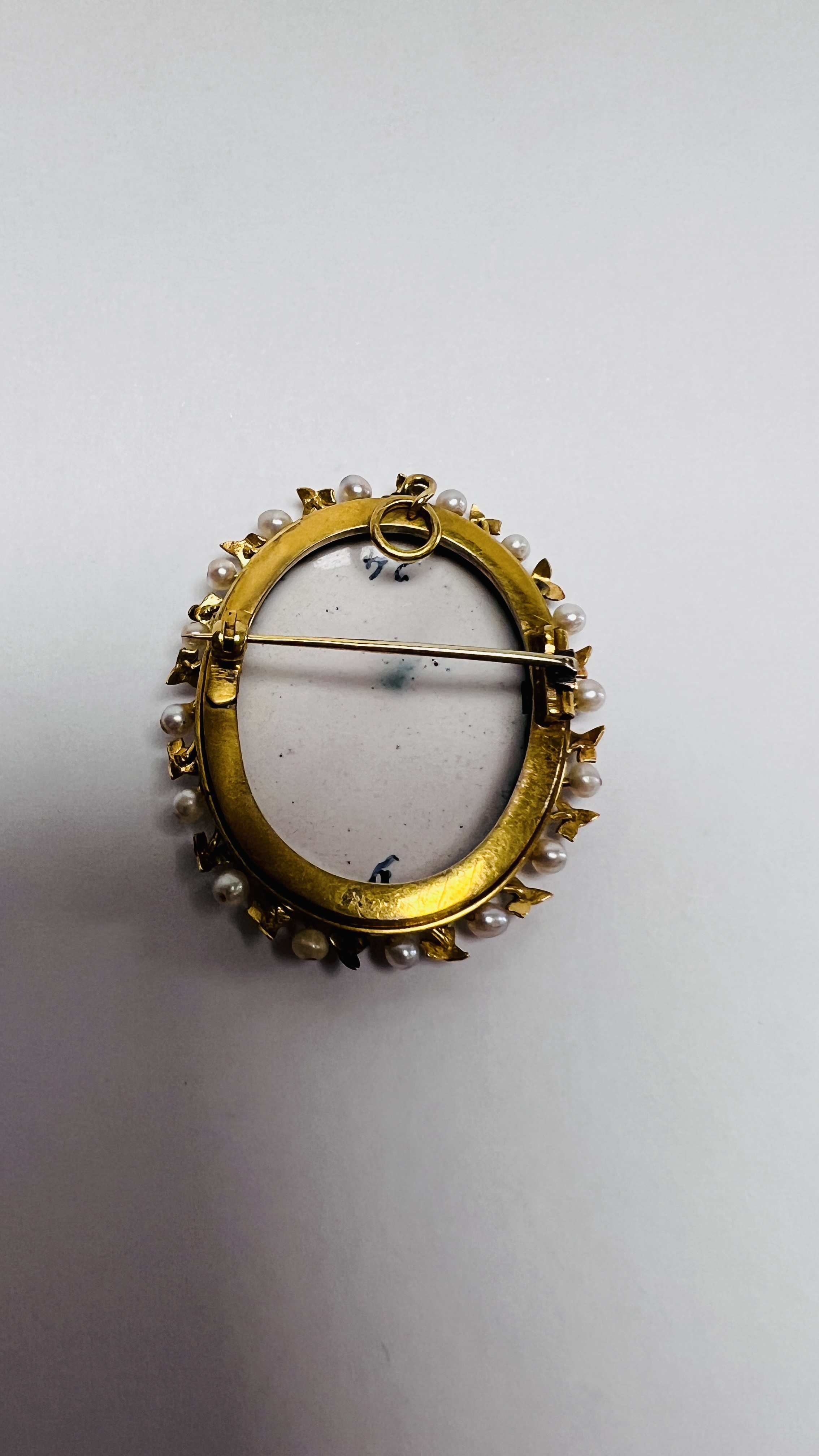 A VINTAGE YELLOW METAL OVAL PORCELAIN PENDANT BROOCH SURROUNDED BY SEED PEARL AND ENAMELLED DETAIL - Image 6 of 8