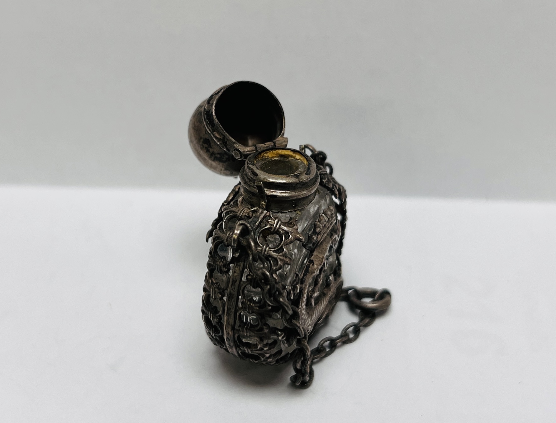 A MINIATURE ANTIQUE CUT GLASS SCENT BOTTLE ENCASED IN AN ORIENTAL WHITE METAL HOLDER - Image 6 of 7