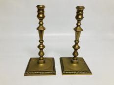 A PAIR OF LATE GEORGE III BRASS CANDLESTICKS ON A SQUARE BASE HEIGHT 25CM.