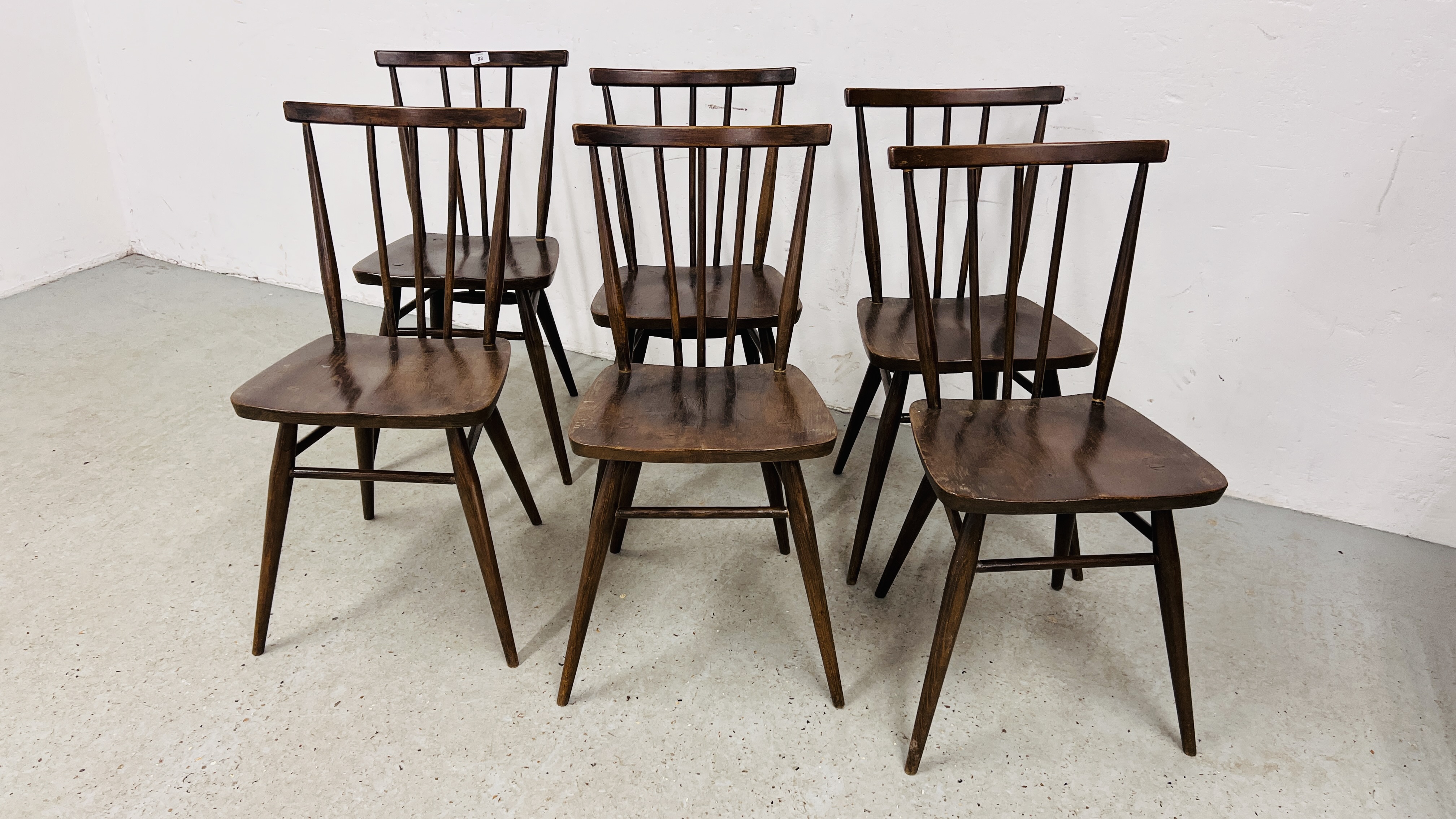 A SET OF SIX DARK ERCOL STICK BACK DINING CHAIRS, 1 A/F.