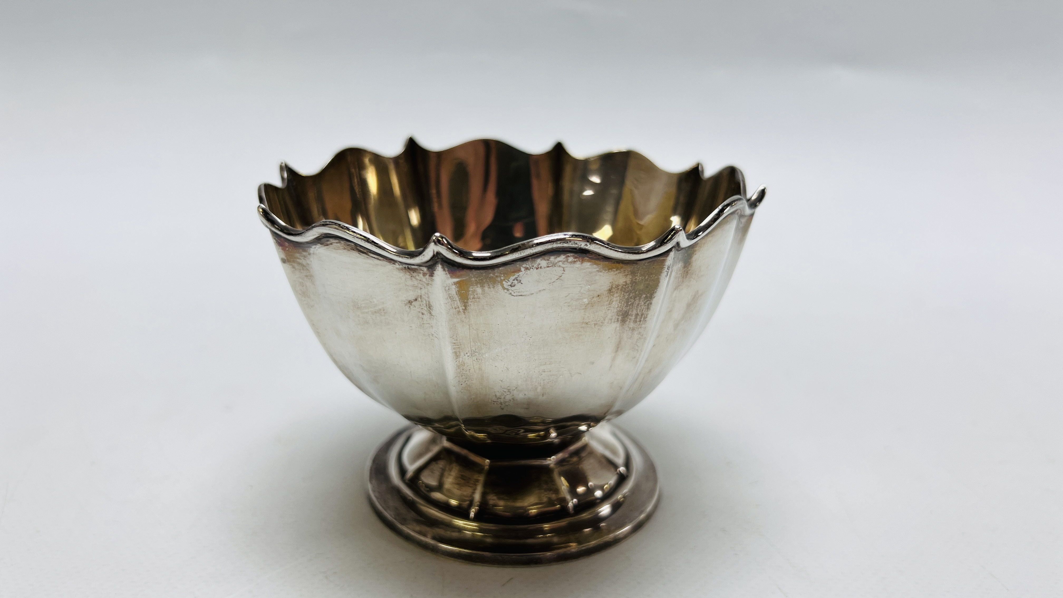 A SILVER FACETED BOWL WITH WAVY RIM ON CIRCULAR DOMED BASE SHEFFIELD 1909 HEIGHT 8.5CM.