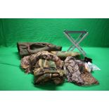 A LARGE GREEN CANVAS DECOYING BAG ALONG WITH LIGHT WEIGHT FOLDING STOOL, CAMO HIDE NETS, HATS,